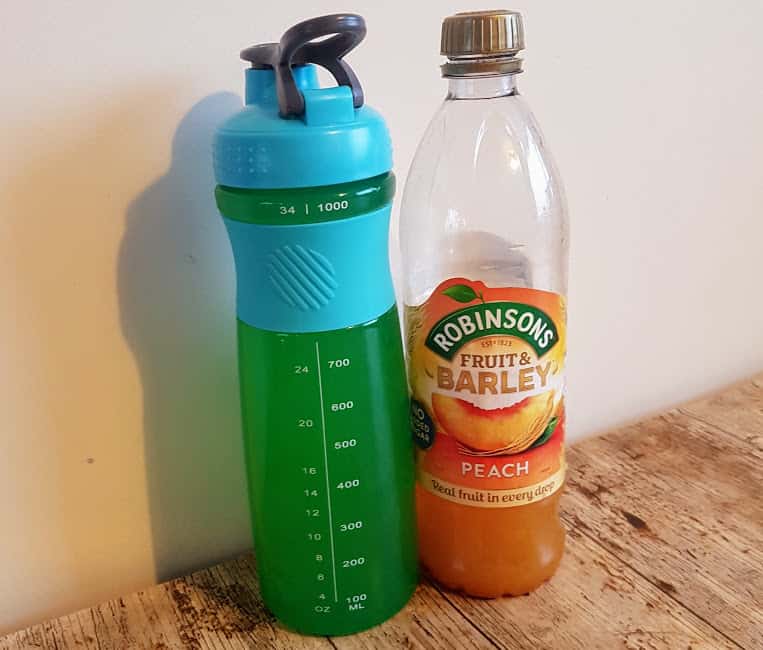 Bottle of peach fruit and barley with a plastic water bottle