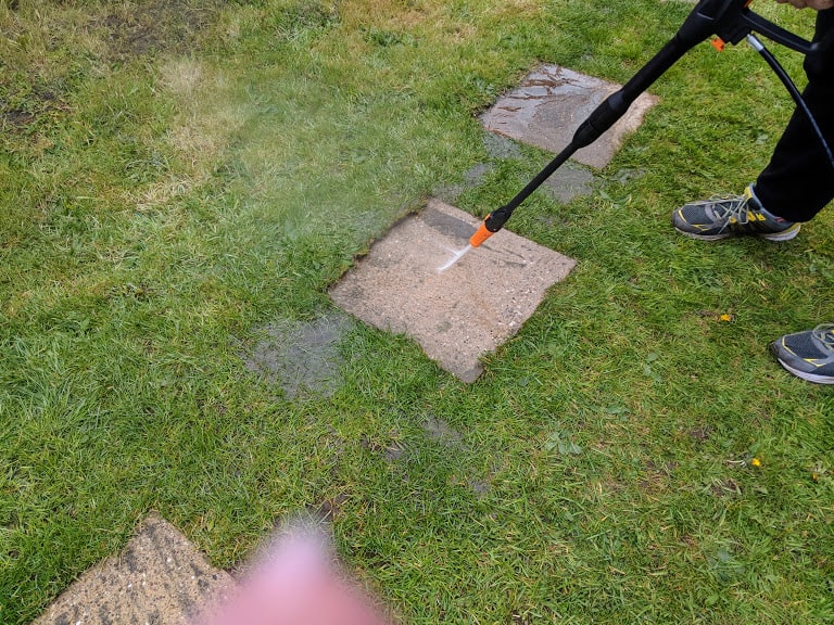 Person pressure washing a slab in their garden