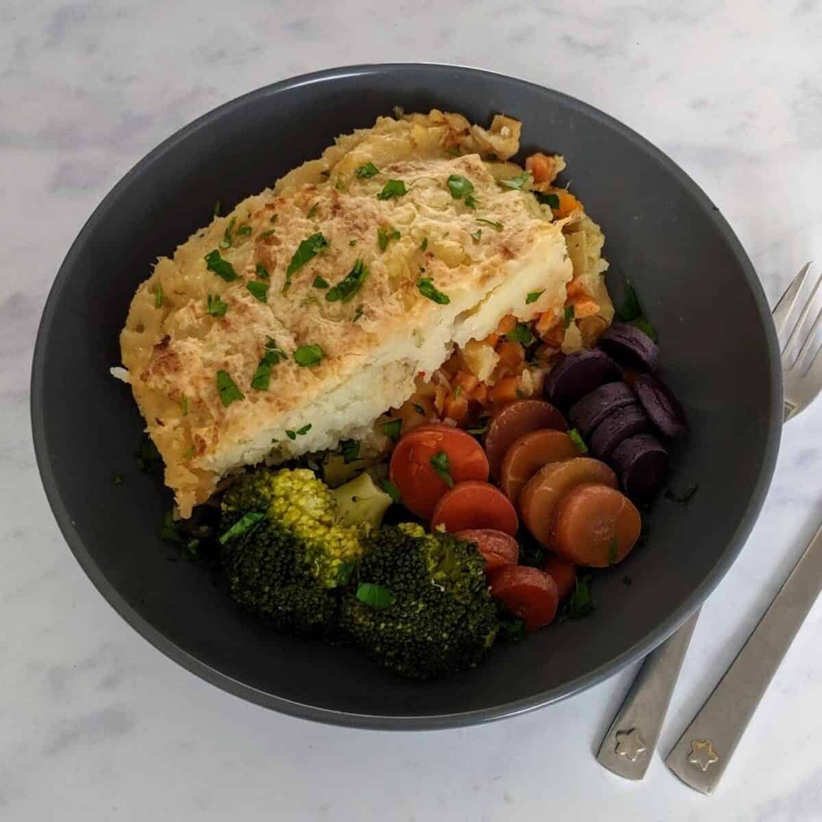 Gardeners pie in a bowl with carrots and broccoli