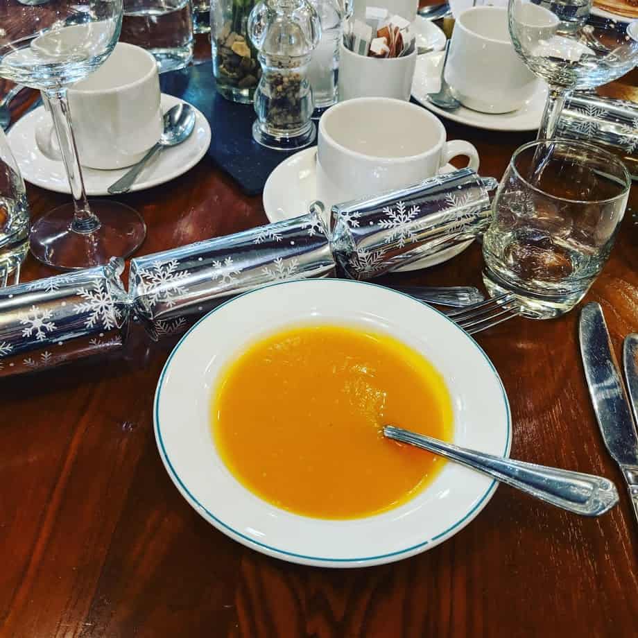 A bowl of soup on a table of cups and glasses