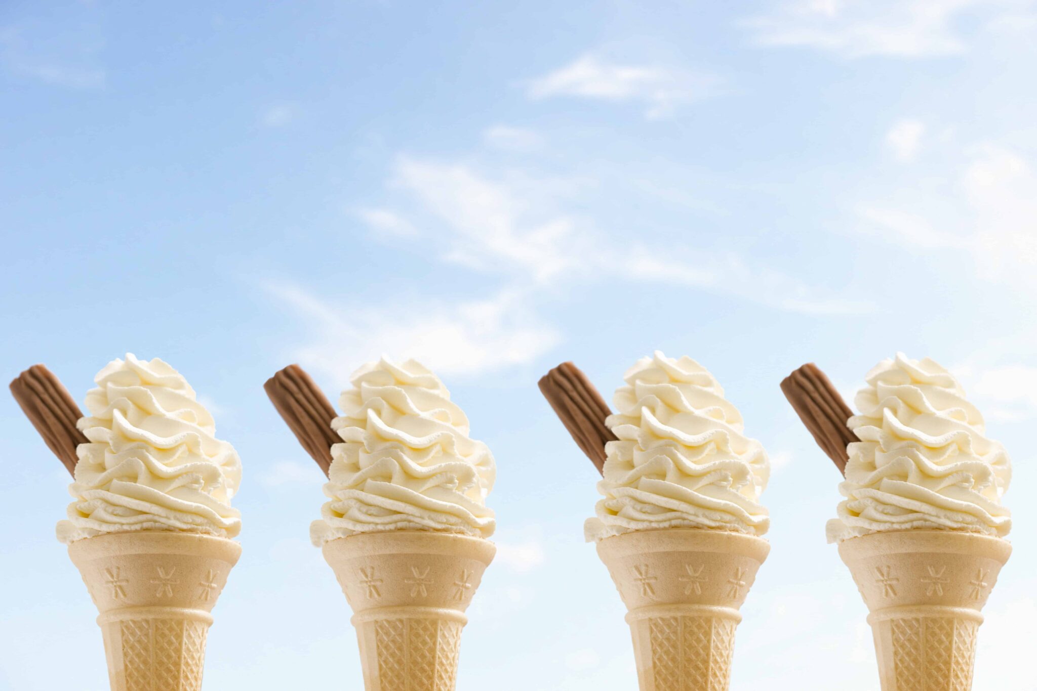 four ice creams with bright blue sky in the background