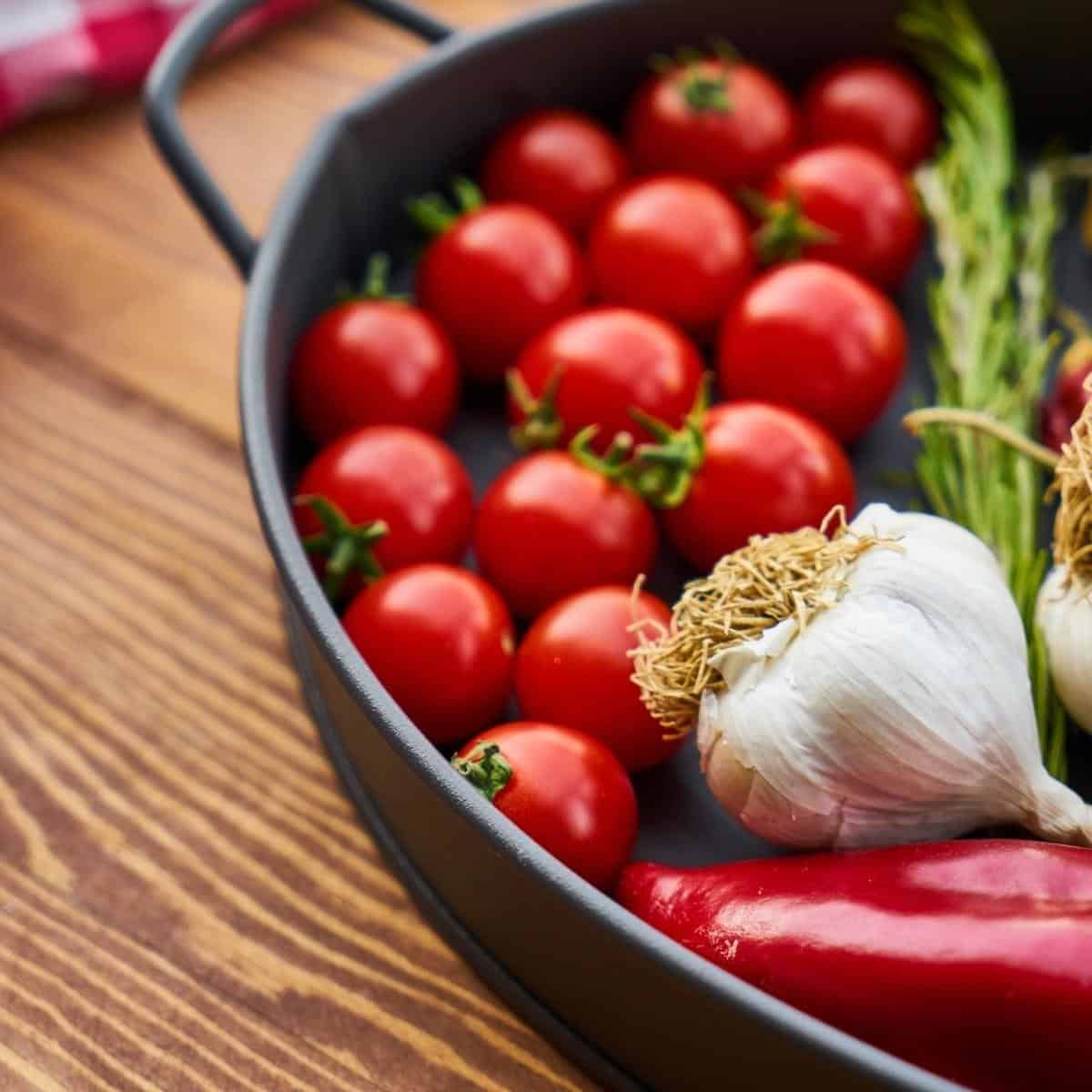 Mediterranean vegetables - cherry tomatoes, garlic and red pepper in a skillet.