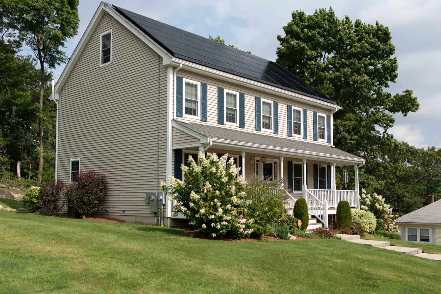 Large house with bushes and grass in front