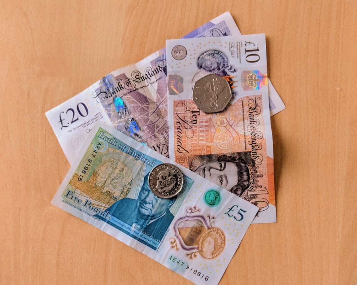 A mixture of British currency notes and coins on wooden table