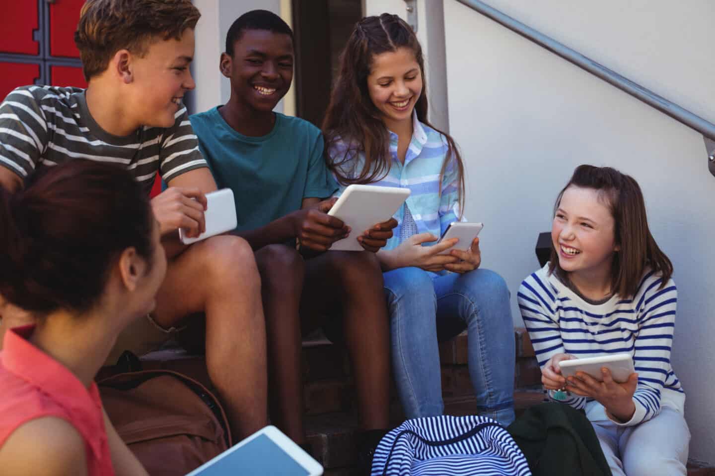Group of teenagers playing on phones and tablets