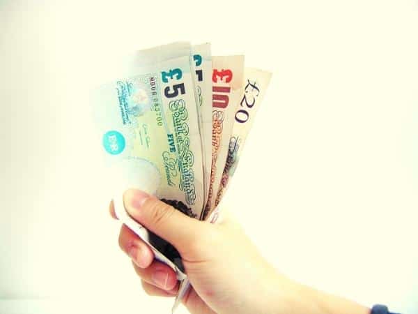 Hand holding all the money it costs to do the plan