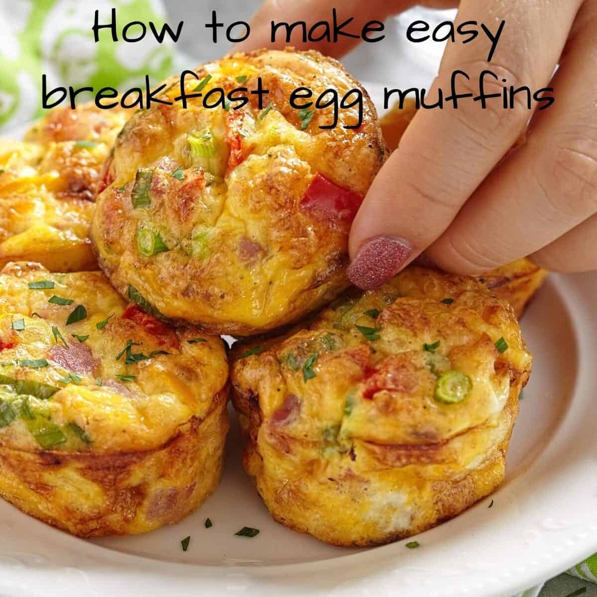 A hand picks up a breakfast egg muffin from a plate of muffins. The text on the image reads: “how to make easy breakfast egg muffins. ”.