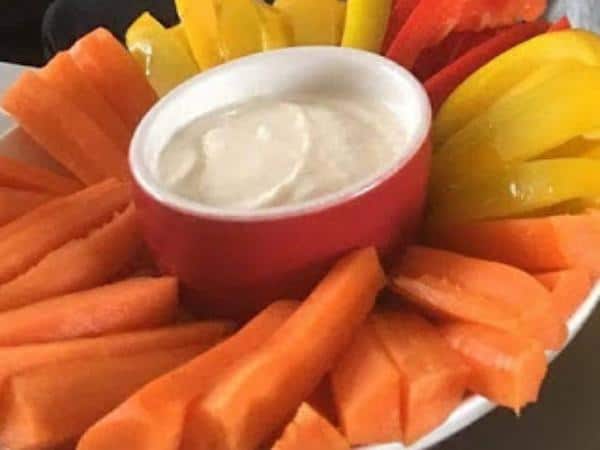 Dip surrounded by carrot and pepper sticks