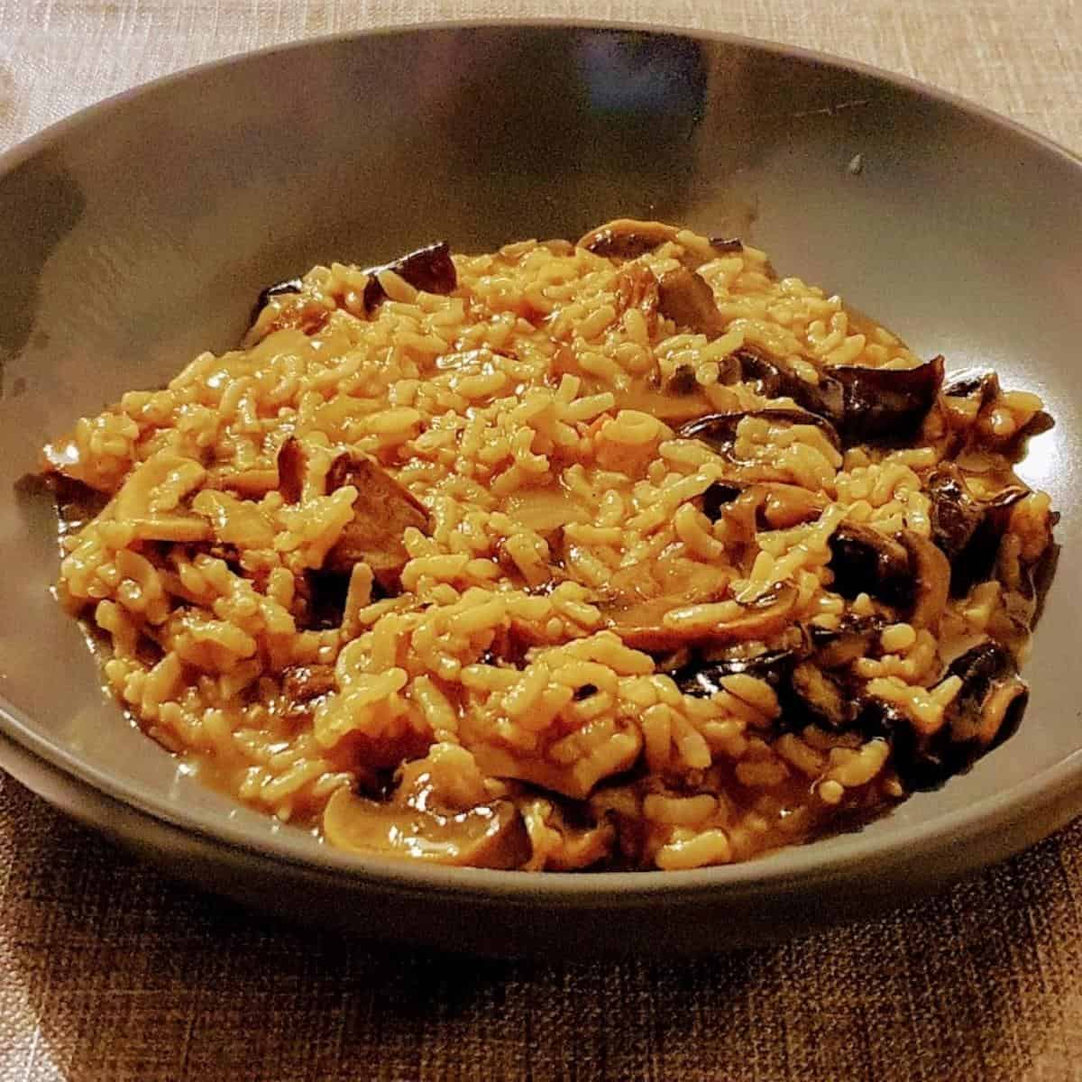 A bowl of food on a plate, with Mushroom and Risotto
