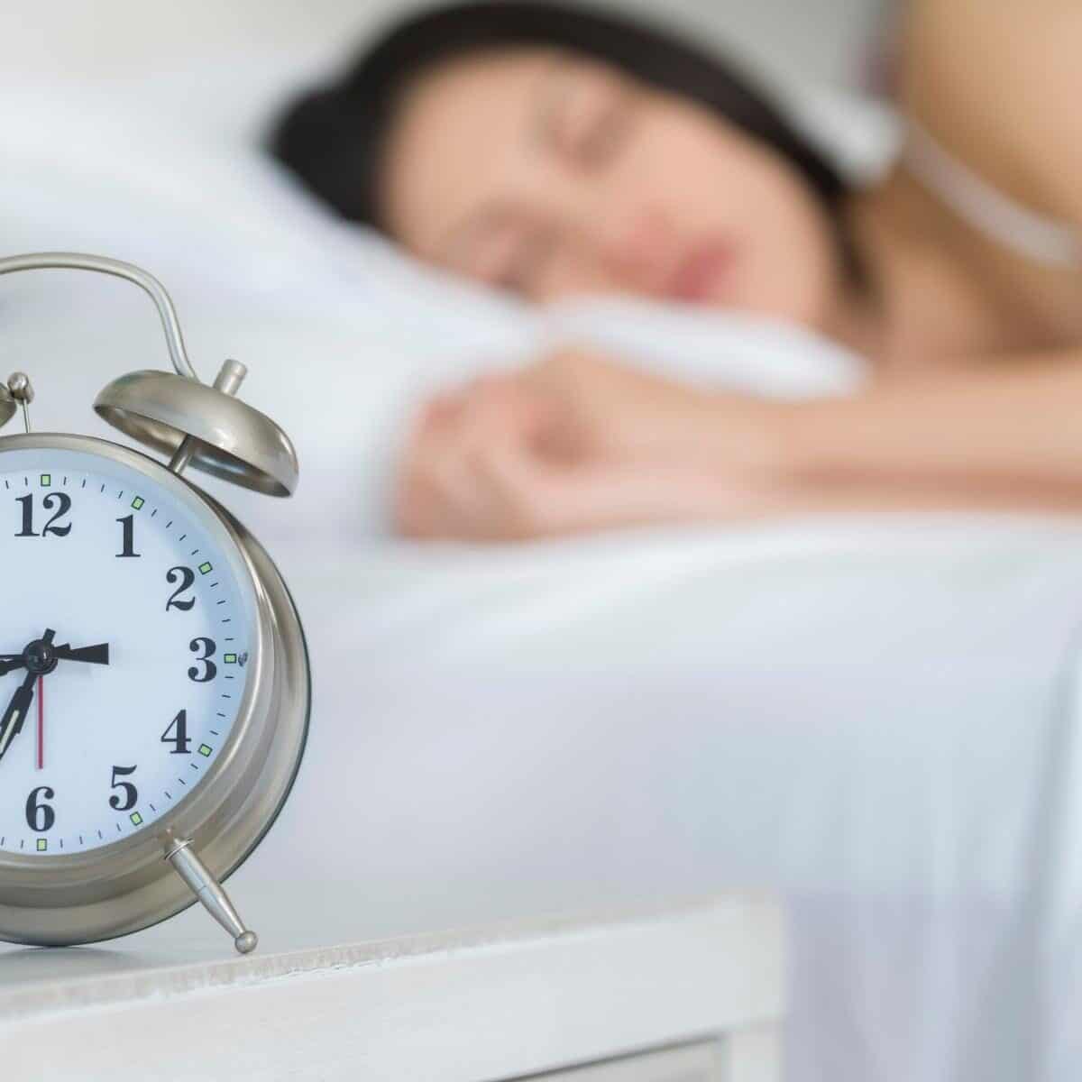 Lady asleep with alarm clock next to her