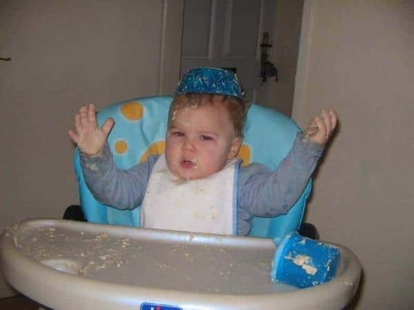 Ben aged 8 months covered in porridge in a highchair