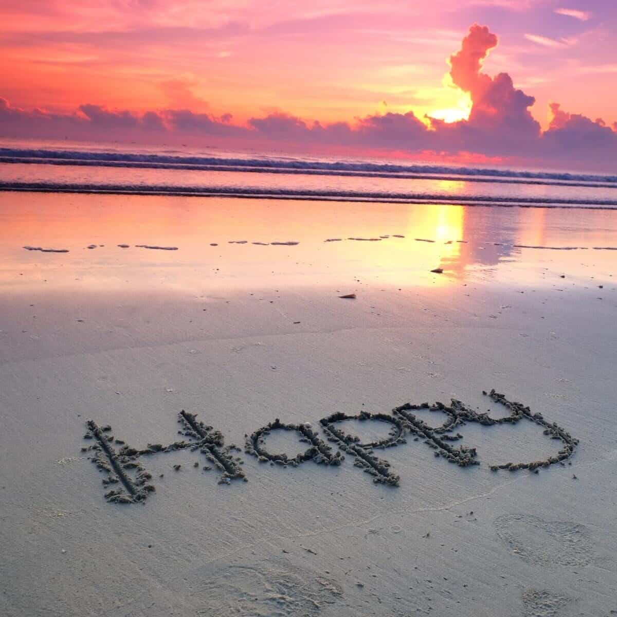 happy written in the sand at sunset