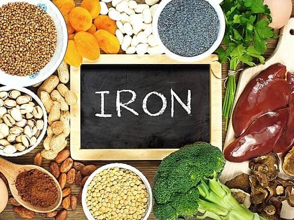 Iron rich foods on a table surrounding a chalkboard with iron written in chalk
