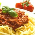 Spaghetti Bolognese in a bowl topped with a sprig of basil.