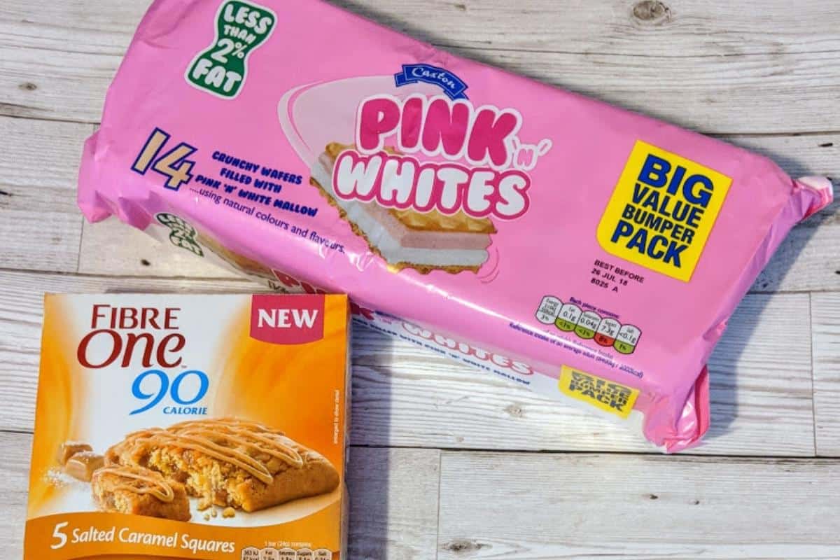 A package of Pink'n'Whites and a box of Fibre One Salted Caramel Squares sit on a wooden surface, perfect for a Slimming World taster session.