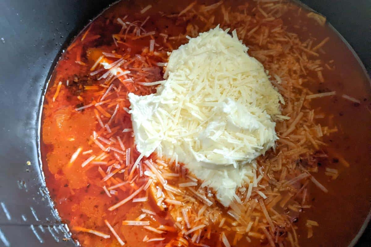 cheese and cream cheese on a tomato sauce in an Instant Pot.