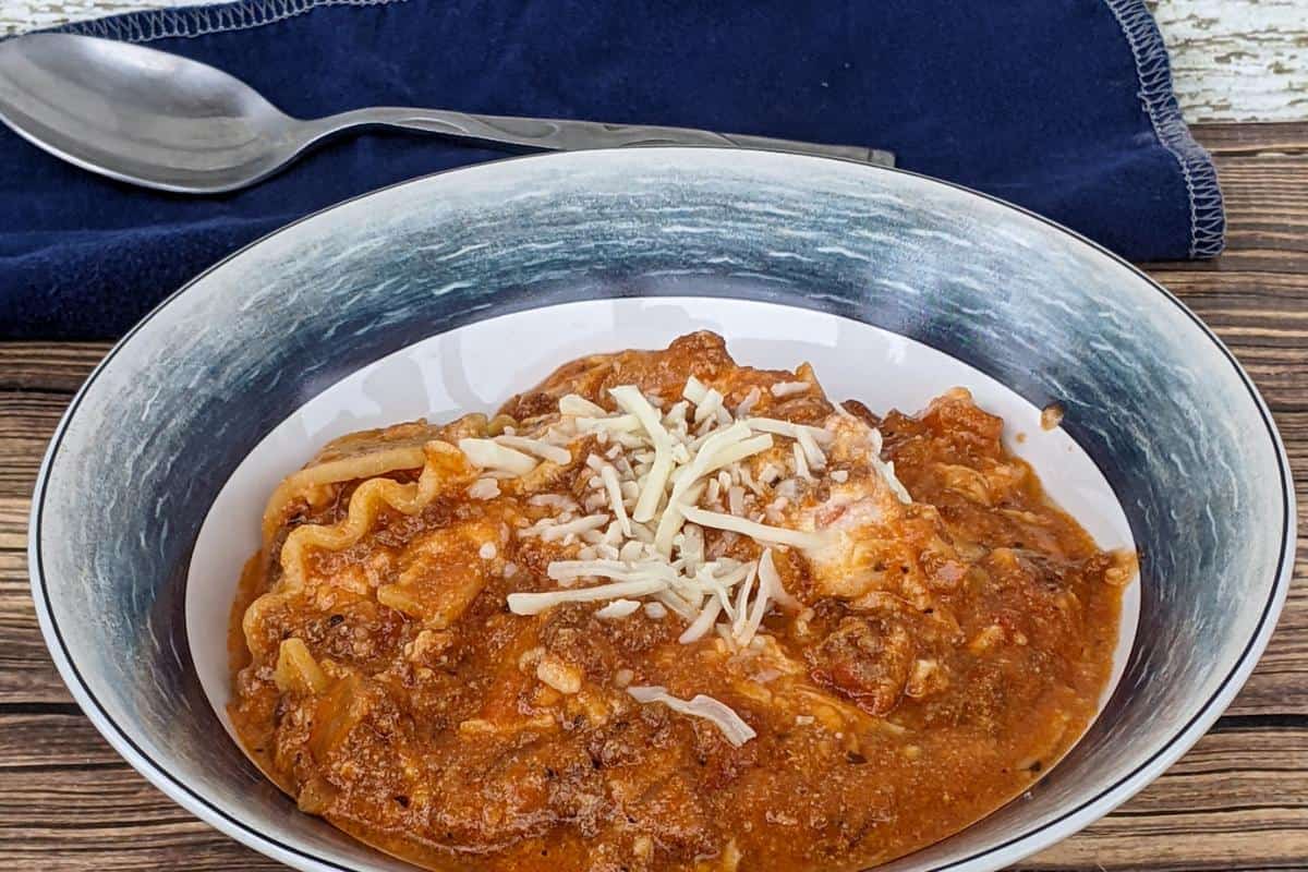 A bowl of cooked lasagne soup topped with a sprinkle of cheese.