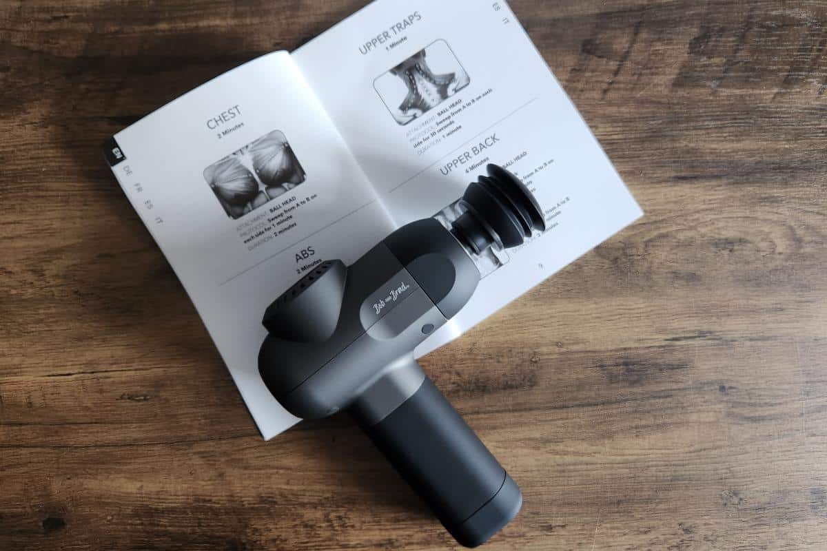 A black massager which is wireless with its instruction booklet.