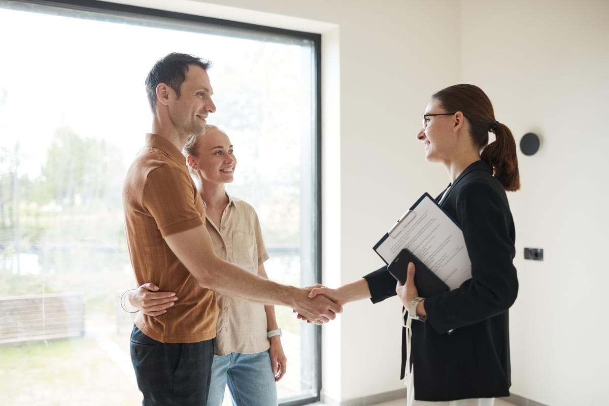 house buying a couple shaking hands with an estate agent.