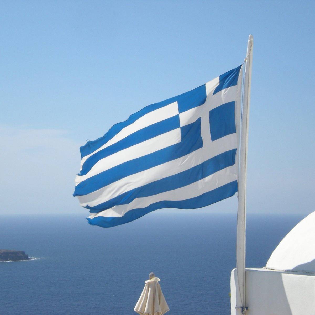 The Greek Flag in front of a blue sea.