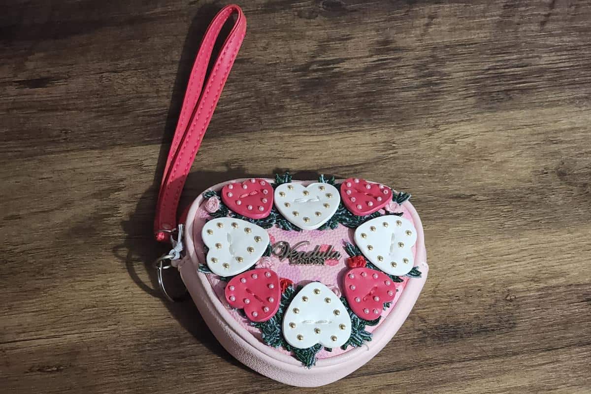 A heart shaped coin purse in pink with white and dark pink hearts and foliage in a 3d design from the brand Vendula.