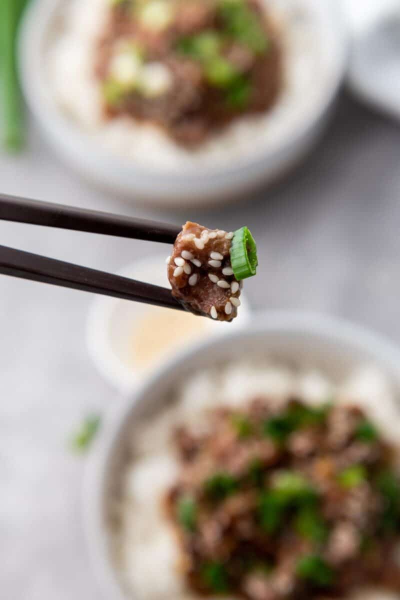 chop sticks holding a piece of Mongolian Beef.