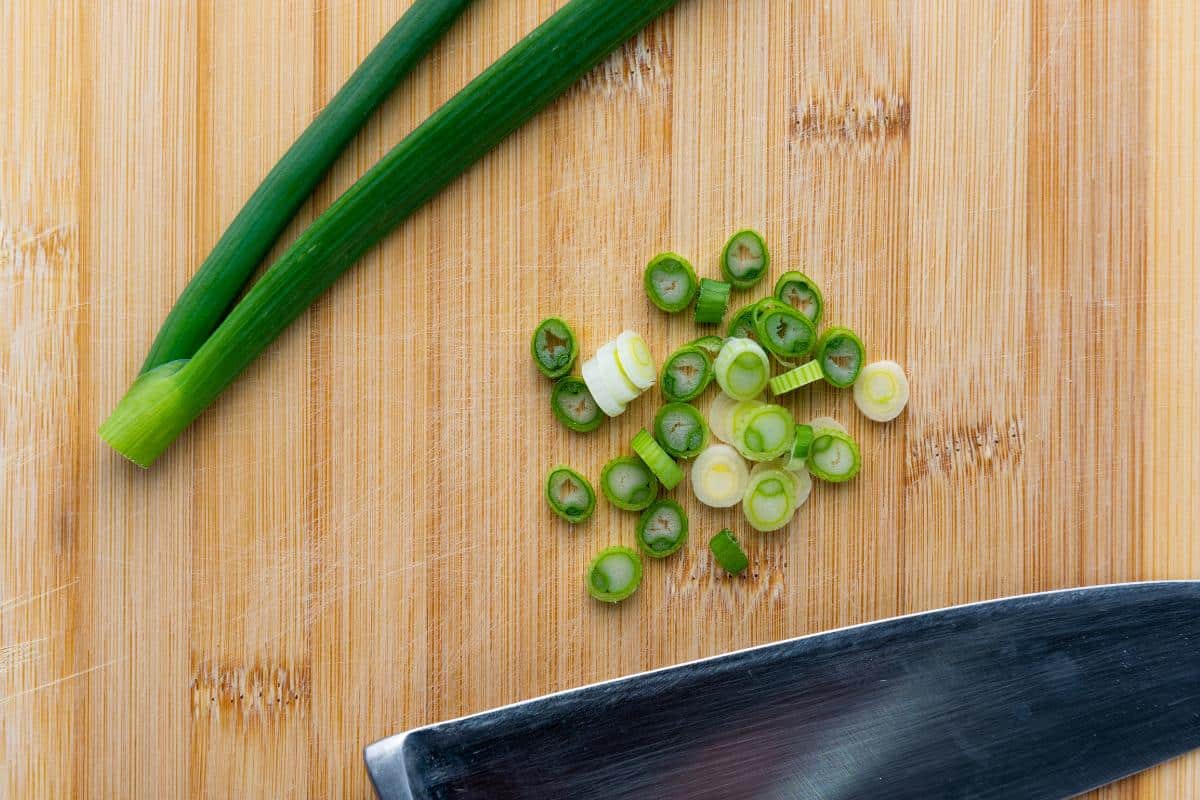 Sliced spring onions on a wooden board.