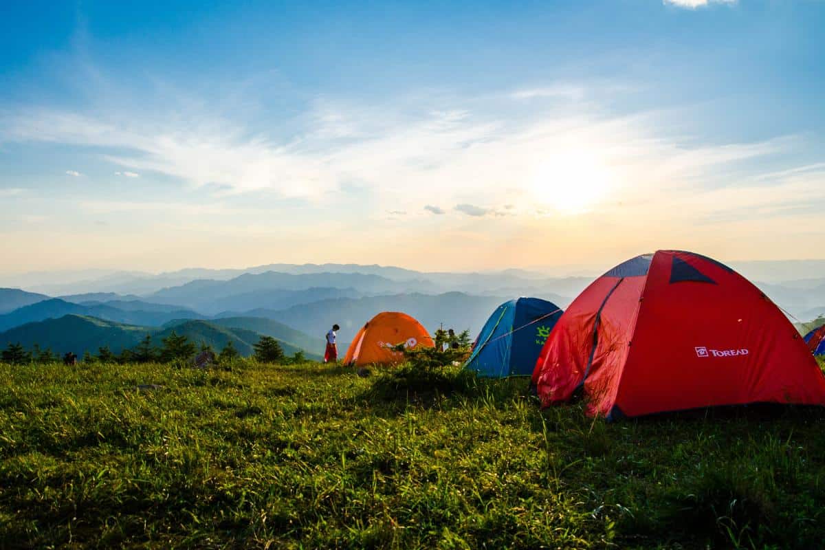 Row of tents for camping with hills and mountains in the background.