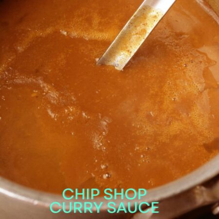 A close-up of a saucepan filled with brown curry sauce, with a metal ladle resting inside. The words “chip shop curry sauce” are overlaid at the bottom.