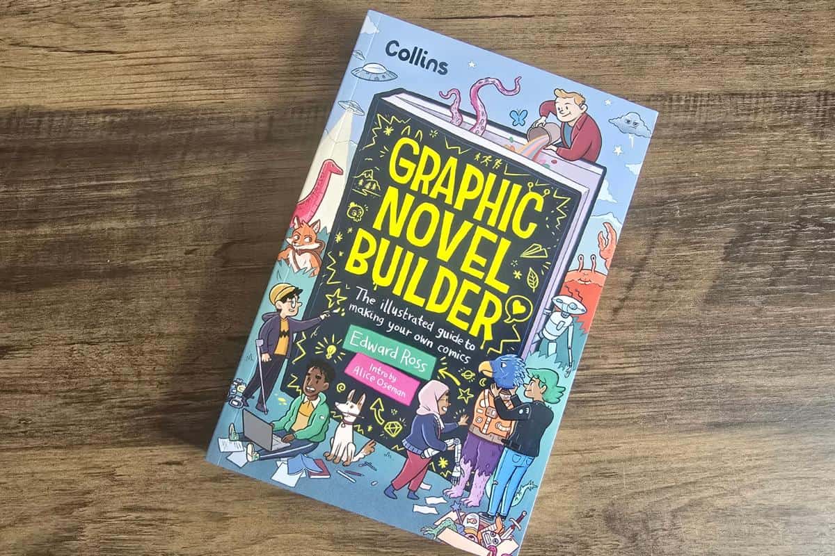 A book titled "Graphic Novel Builder" by Edward Ross sits on a wooden surface, featuring colorful illustrated characters on the cover. This captivating addition to books for children sparks creativity and imagination with every page.