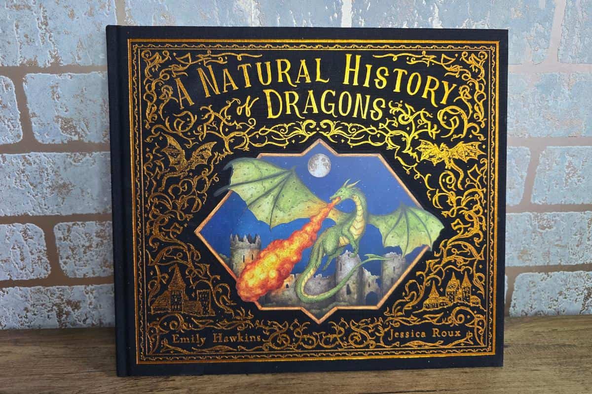 Cover of "A Natural History of Dragons" by Emily Hawkins and Jessica Roux, a captivating book for children, featuring an illustrated dragon breathing fire against a medieval backdrop.