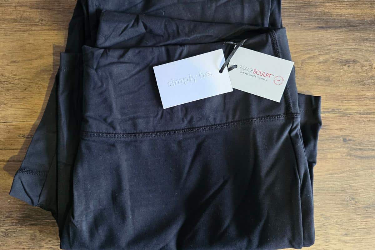Black exercise clothes with tags, ideal for plus size women, neatly folded on a wooden surface.