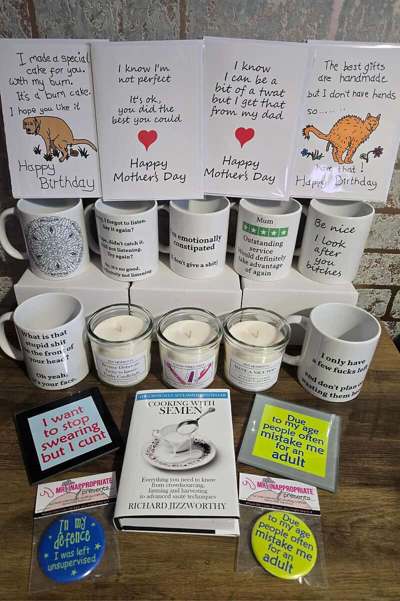 A collection of humorous mugs, cards, candles, coasters, and an entertaining book with playful quotes is arranged on a table. Perfect for those who appreciate rude gifts with a cheeky twist.