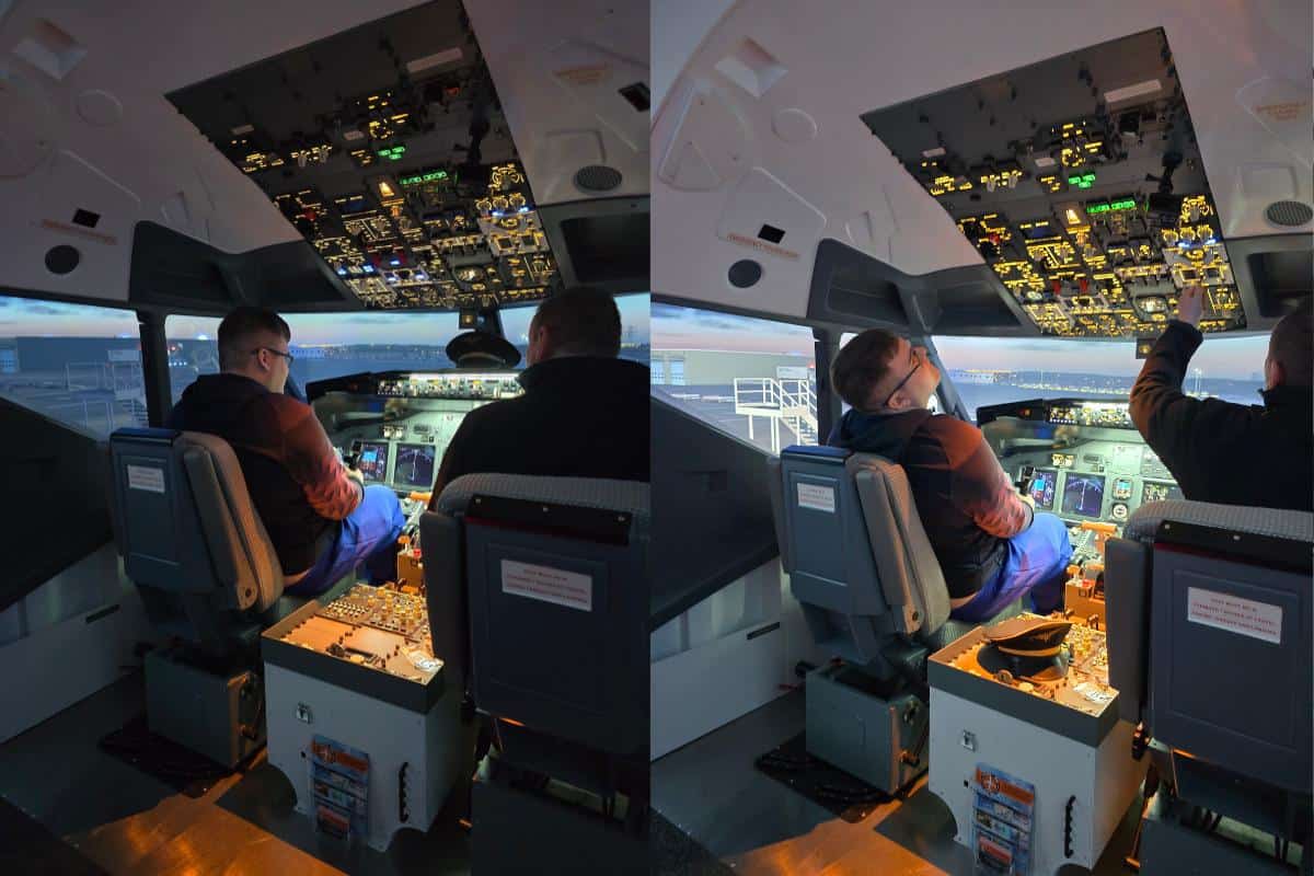 Two people are seated in the cockpit of a FlightSimCentre aircraft simulator. One operates the controls while the other points at the overhead panel. The simulator offers an authentic Flight Simulator experience, surrounded by a realistic airport backdrop visible through the windows.