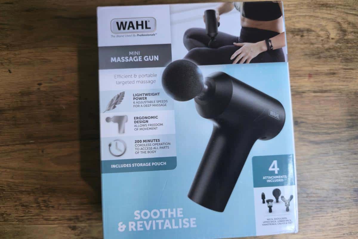 A box for a WAHL mini massage gun sits on a wooden surface. The packaging highlights features like lightweight power and ergonomic design—making it one of the best gift ideas for dad. The box reads "Soothe & Revitalise" with images and descriptions.