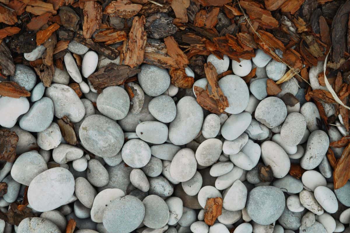 A close-up view of mulch and stone. The textures of the rocks and wood pieces create a natural contrast, perfect for front yard landscaping.