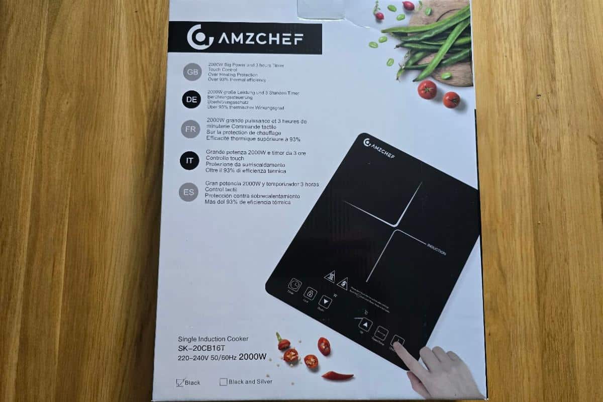 A box for an AMZCHEF single induction hob showcases compact convenience, with product details in multiple languages, an image of the cooker, scattered vegetables, and a hand pressing a button on the appliance.