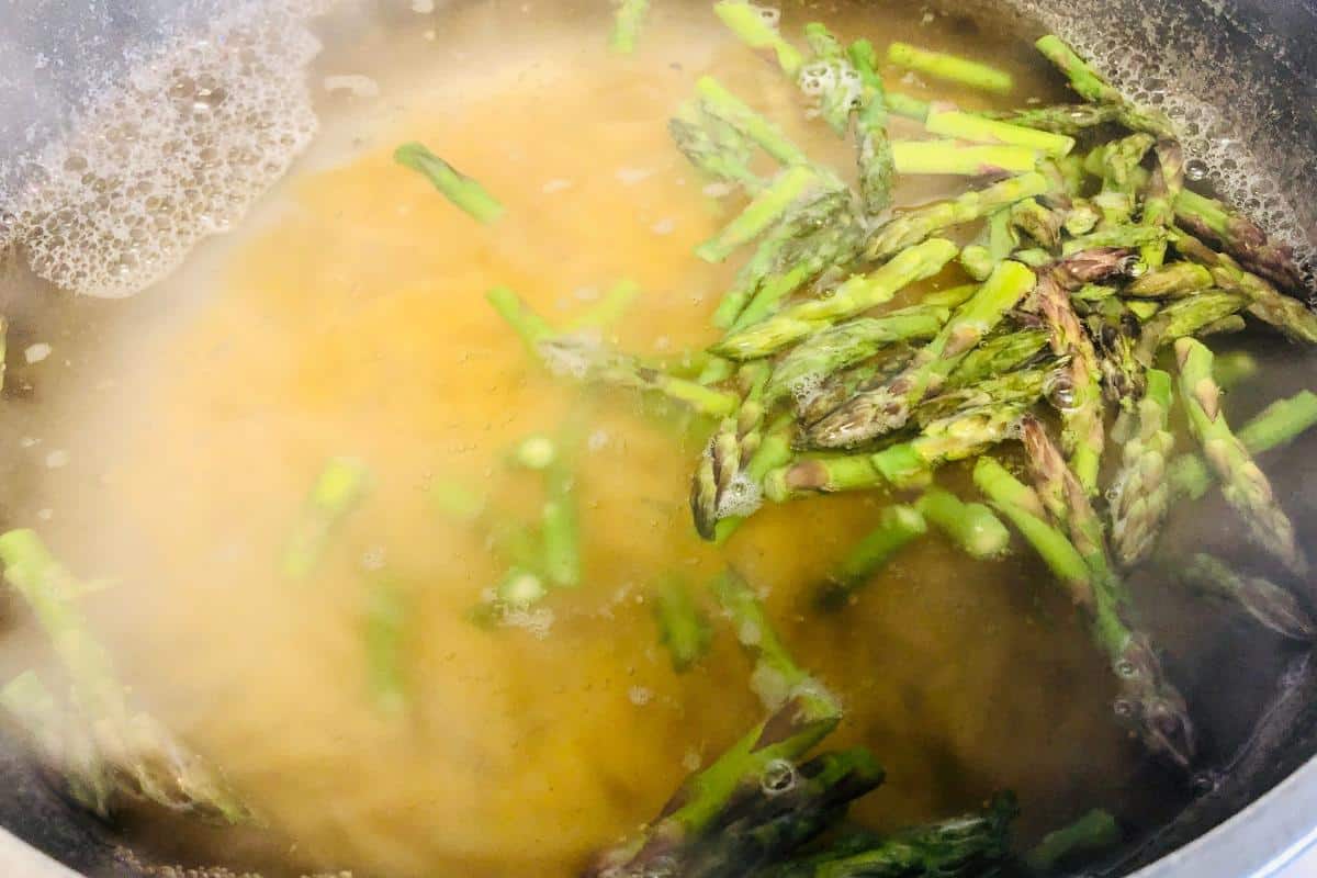 Pasta and asparagus pieces boiling together in a pot of water, with steam rising from the surface—a perfect start for healthy pasta recipes.