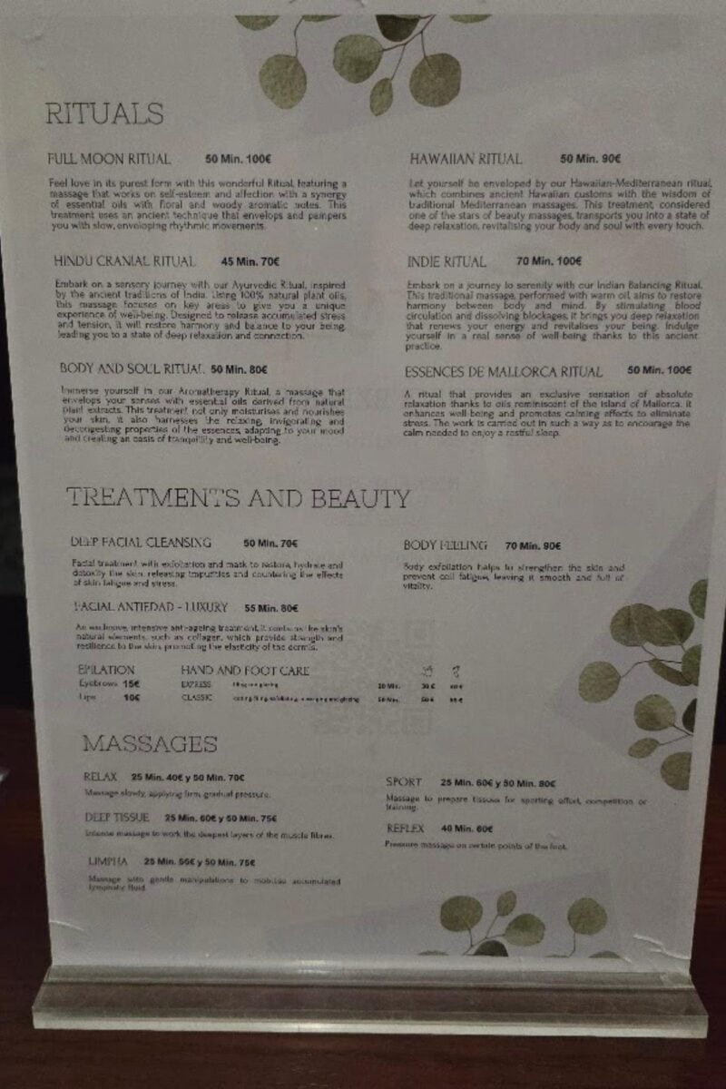 Menu displaying spa services, including rituals, treatments, beauty services, and massages, with descriptions, durations, and prices. Set against delicate green leaves at Bahia del Sol in Santa Ponsa—ideal for your all-inclusive relaxation experience.