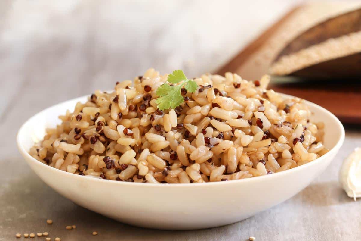 A white bowl filled with cooked brown rice.