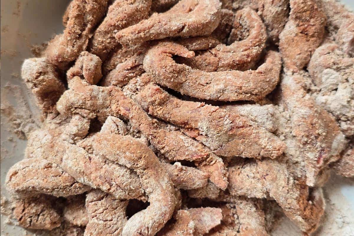 A close-up of uncooked strips of meat coated in flour and seasoning, arranged in a pile, ready for frying or cooking—perfect for your Healthy Fakeaway Sticky Beef Recipe.
