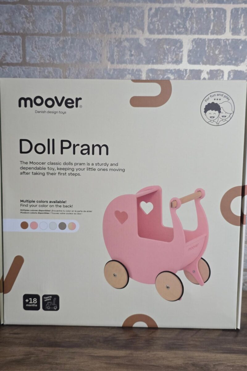 A box for a Moover Doll Pram features a pink toy pram with wooden wheels and heart cutouts. With brown and beige packaging, it's highlighted in the children's Christmas gifts guide as perfect for ages 18 months and up, with multiple color options available.