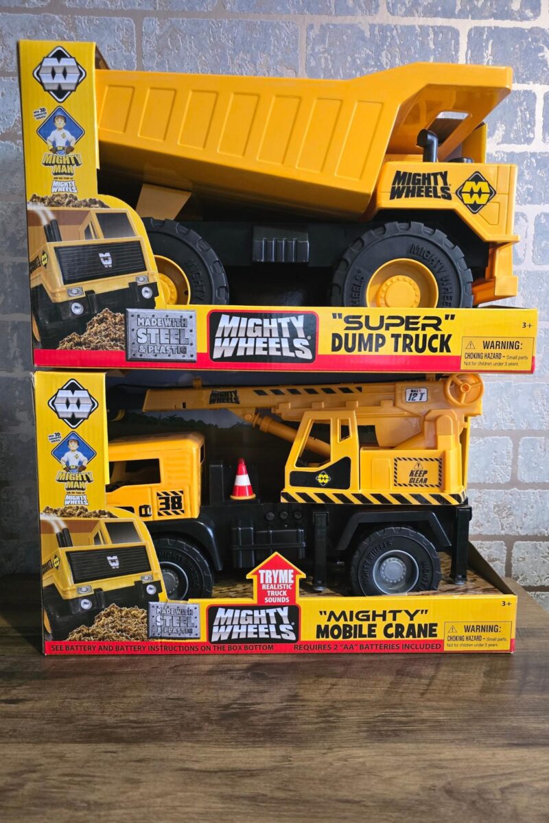 Two yellow toy construction vehicles in boxes—a "Super Dump Truck" and "Mighty Mobile Crane" from Mighty Wheels—are displayed against a brick wall, making them perfect picks for any children's Christmas gift guide.