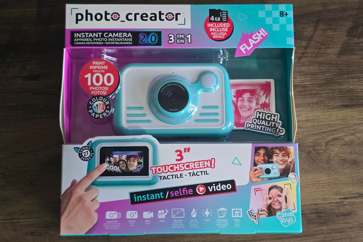 A boxed "photo.creator" instant camera toy for kids, perfect for children’s Christmas gifts. Features a turquoise camera with touchscreen display, selfie, video, and instant photo options. Packaging shows smiling kids and fun photo samples.