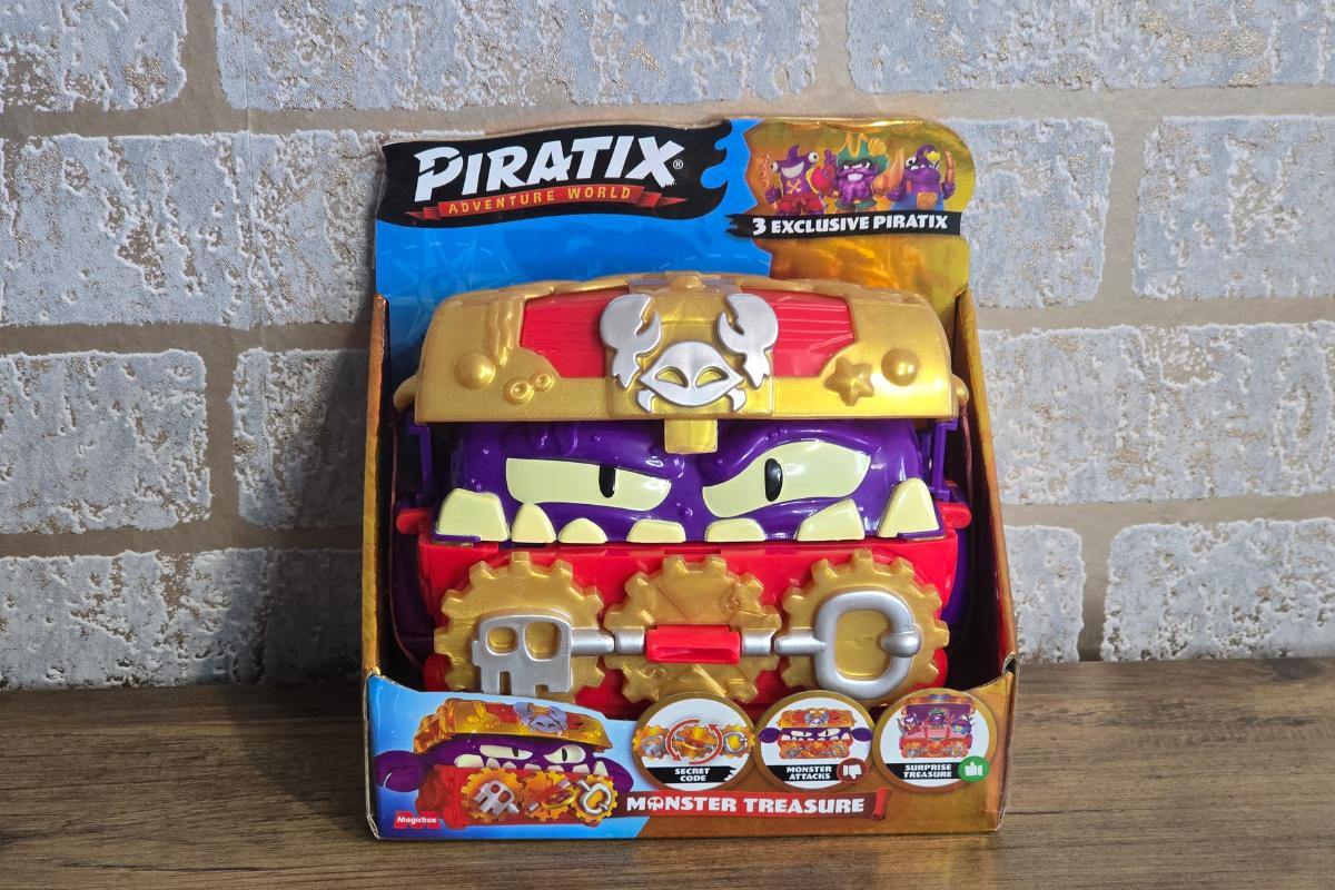 A toy package labeled "Piratix Adventure World" features a colorful, angry-faced treasure chest with gold, red, and purple details—a standout choice for children's Christmas gifts—shown against a brick wall background.
