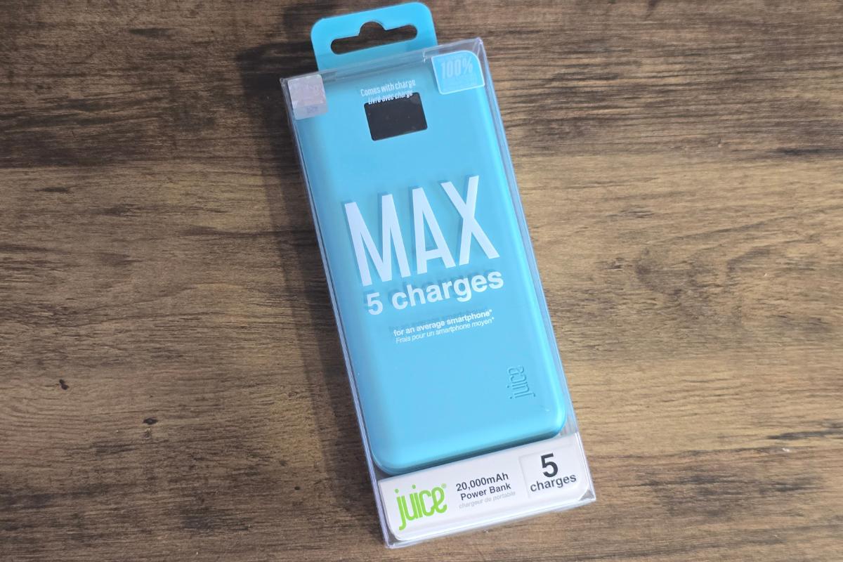 A blue Juice MAX power bank in its packaging is placed on a wooden surface. Ideal as a Secret Santa surprise, the box highlights "MAX 5 charges" and "20,000mAh Power Bank," with "5 charges" noted at the bottom.