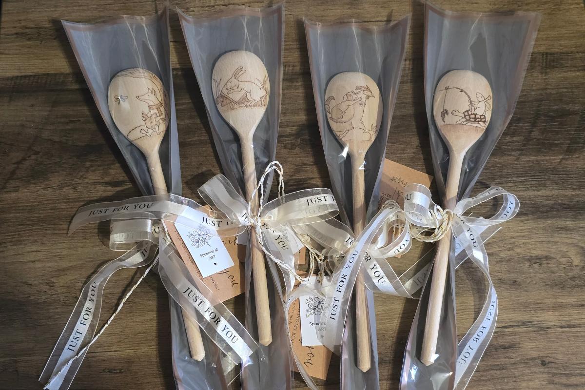 Five wooden spoons with animal engravings are individually wrapped in clear plastic, decorated with ribbons and "JUST FOR YOU" tags—perfect for a thoughtful giveaway or to support your favourite shop small business. Displayed on a wooden surface.