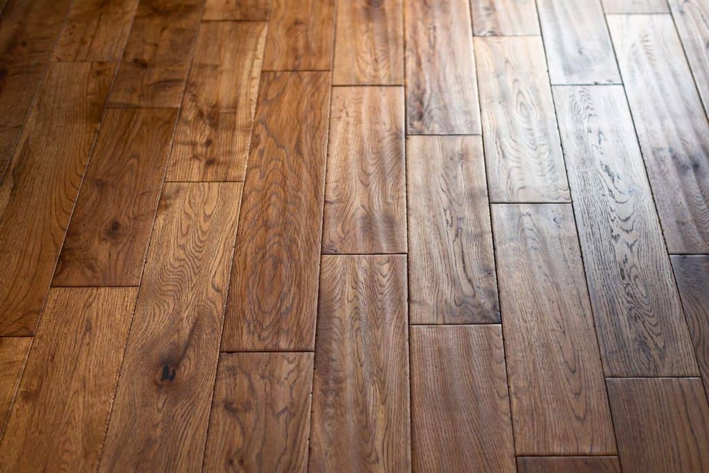 Close-up of wooden floorboards in natural light, showing various shades of brown and visible wood grain patterns.
