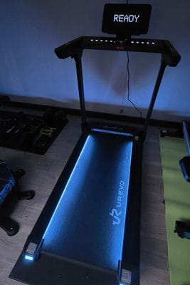 Urevo treadmill with a glowing blue light strip and a display screen that reads “ready”.